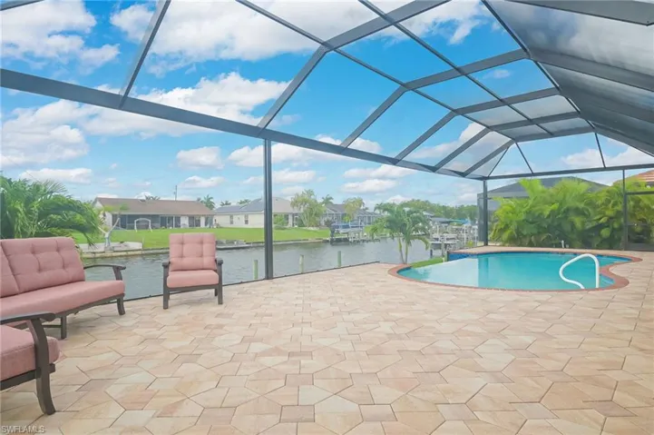 View of pool with a patio area, a lanai, and a water view