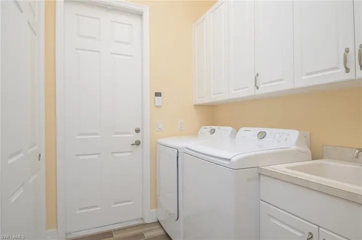 Washroom featuring sink, washer and dryer, and cabinets