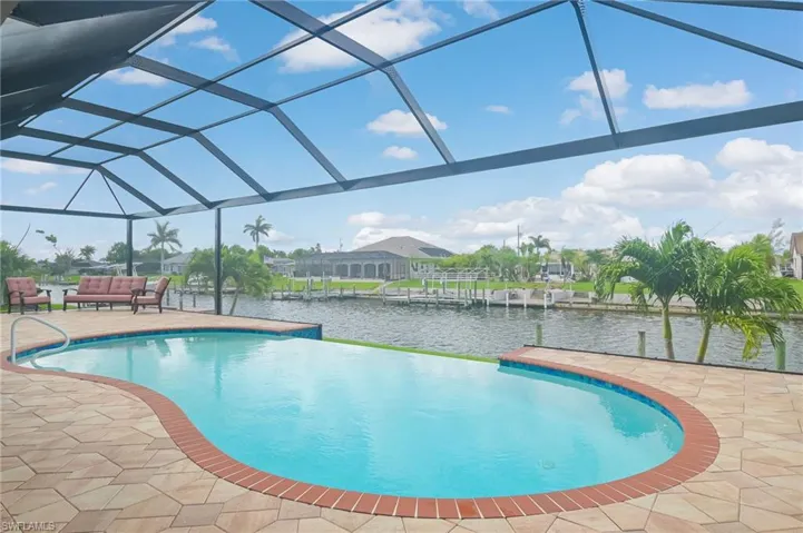 View of swimming pool with a patio, glass enclosure, a water view, and an outdoor living space
