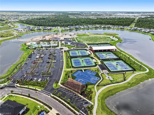 Aerial recreation complex featuring multiple tennis courts, a basketball court, surrounding water features, and expansive paved parking areas