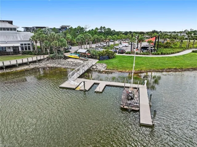 Waterfront property featuring a multi-slip floating dock, metal gangway, and manicured shoreline grass