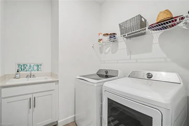 Utility room featuring a built-in cabinet with a drop-in sink, stone-finish countertop, and wire shelving