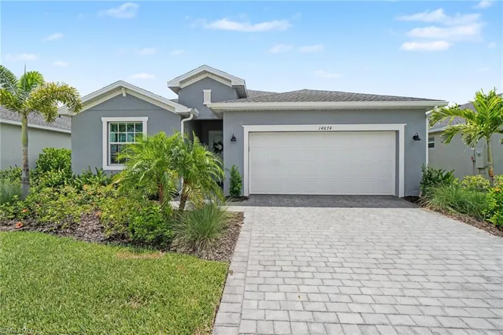 Single-story residence featuring a painted stucco exterior, paver driveway, two-car garage, and landscaped front yard