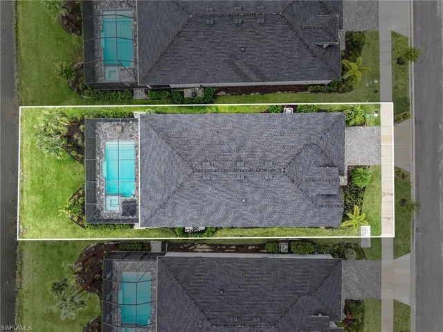 Aerial perspective featuring a shingle roof, screened-in swimming pool, stone-paver pool deck, and landscaped lawn