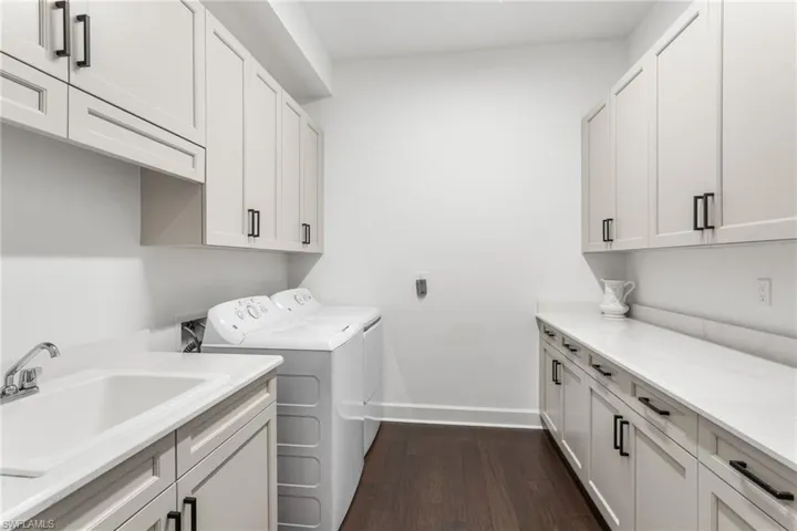 Laundry area with cabinet space, dark wood-style floors, and washing machine and dryer