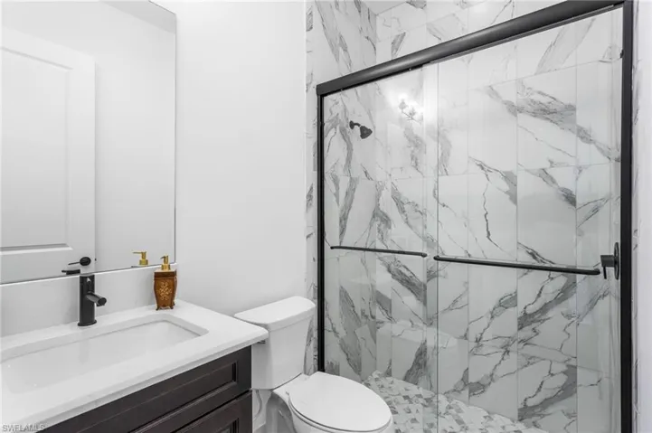 Bathroom featuring vanity and a marble finish shower