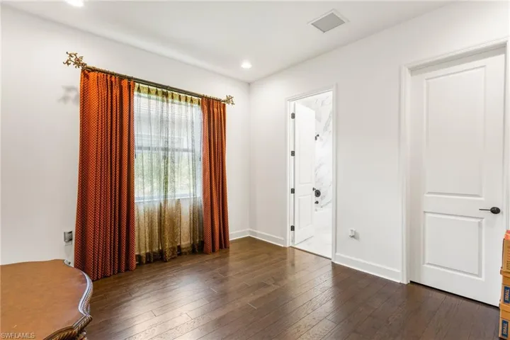 Unfurnished bedroom with dark wood finished floors, ensuite bathroom, and recessed lighting