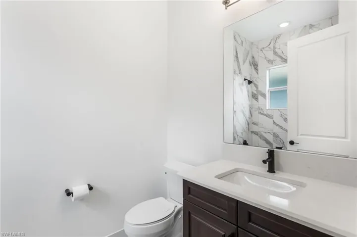 Bathroom with vanity and a marble finish shower