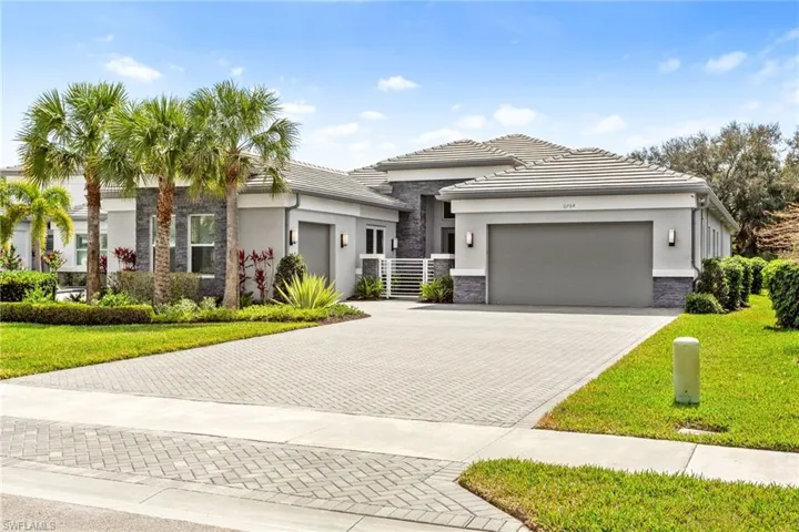 Prairie-style home with stone siding, a front lawn, decorative driveway, and an attached garage