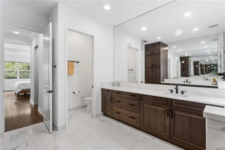 Bathroom featuring light marble finish floors, vanity, recessed lighting, and connected bathroom