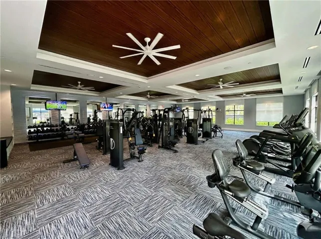 Exercise room with a wooden tray ceiling, a ceiling fan, and recessed lighting