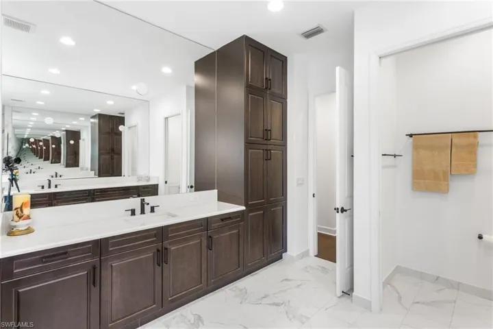 Full bath with vanity, light marble finish flooring, and recessed lighting