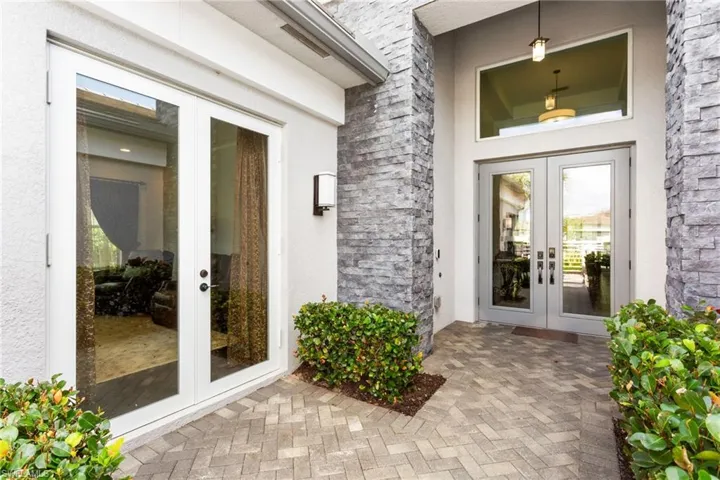 Property entrance featuring french doors, a patio area, stucco siding, and stone siding