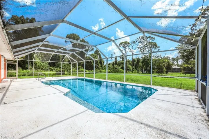 Outdoor pool featuring a patio area, a yard, and a lanai