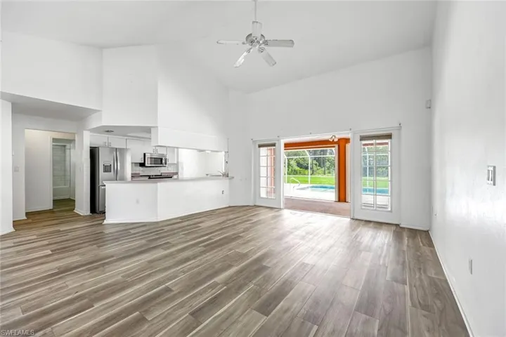Unfurnished living room featuring high vaulted ceiling, ceiling fan, and light wood finished floors