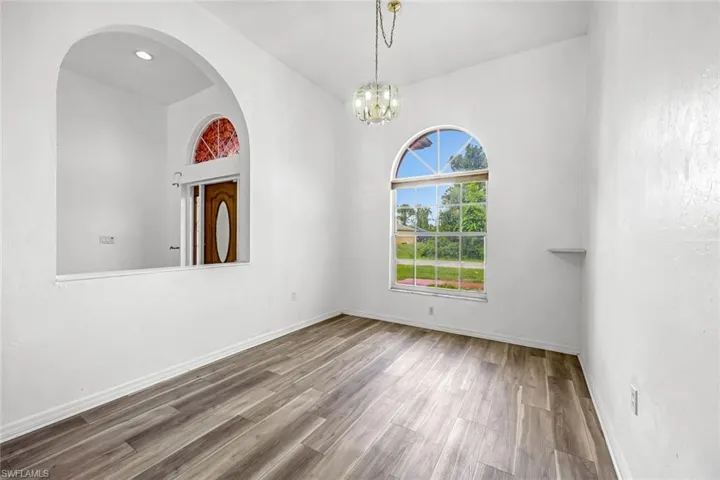 Unfurnished room with wood finished floors, a chandelier, and arched walkways