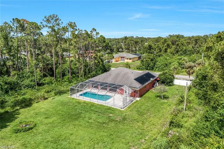Aerial view of property and surrounding area with a pool and a forest