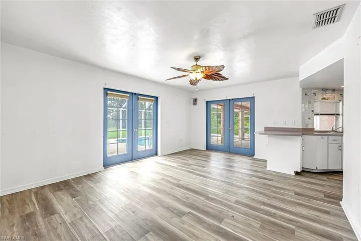 Unfurnished living room with french doors, healthy amount of natural light, a ceiling fan, and light wood finished floors