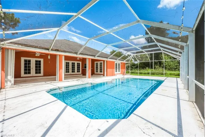 Swimming pool with french doors, a patio, ceiling fan, and glass enclosure