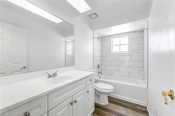 Full bath with vanity, wood finished floors, and shower / washtub combination