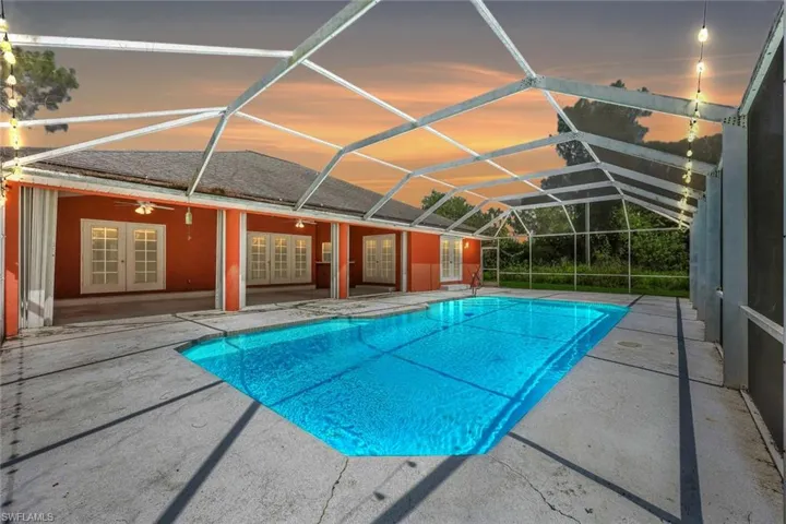 Swimming pool with french doors, a patio, a lanai, and a ceiling fan