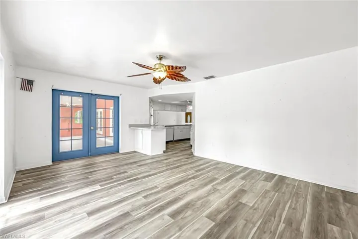 Unfurnished living room with french doors, light wood-style floors, and a ceiling fan