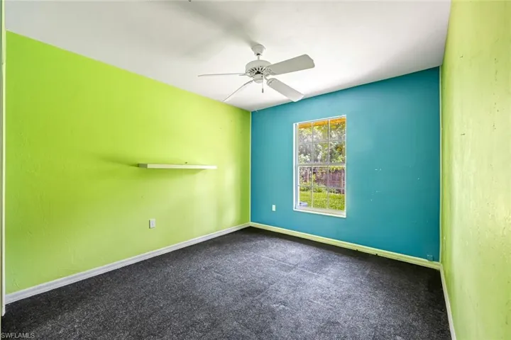 Carpeted spare room featuring ceiling fan and baseboards