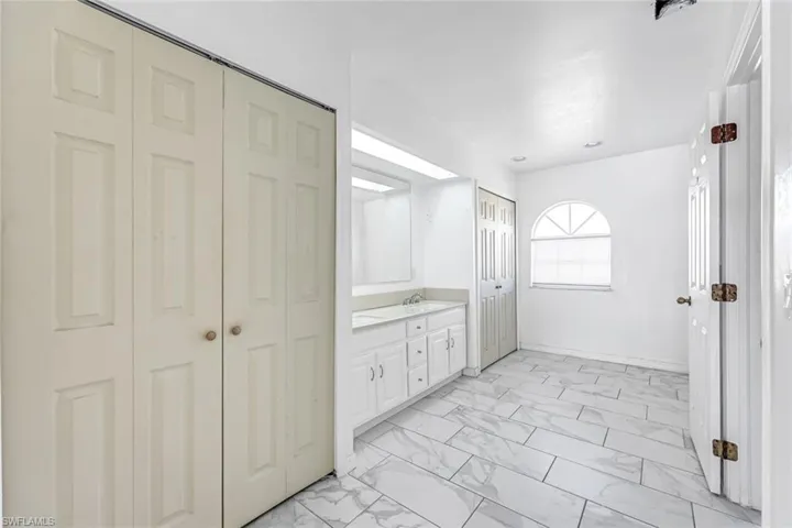 Bathroom featuring a closet, marble look tile flooring, and vanity