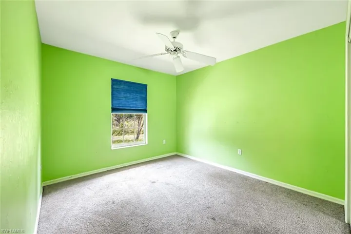 Carpeted spare room with a ceiling fan and baseboards