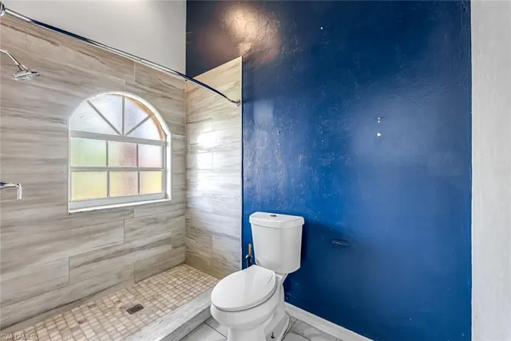 Bathroom featuring tiled shower and toilet