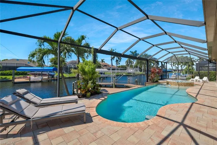 Swimming pool featuring a patio area, a sunroom, boat lift, a water view, and a boat dock