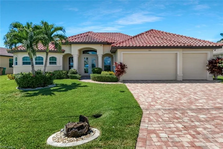 Mediterranean / spanish home with french doors, decorative driveway, a front lawn, and a tiled roof