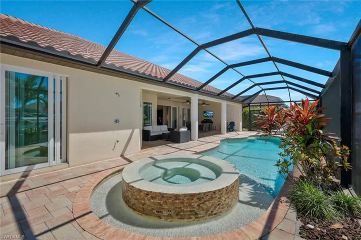 View of swimming pool with a sunroom, a pool with connected hot tub, ceiling fan, a patio area, and glass enclosure