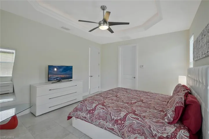 Bedroom featuring a raised ceiling, ceiling fan, and light tile patterned flooring