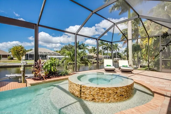 View of pool featuring a water view, a sunroom, a lanai, a patio, and a pool with connected hot tub