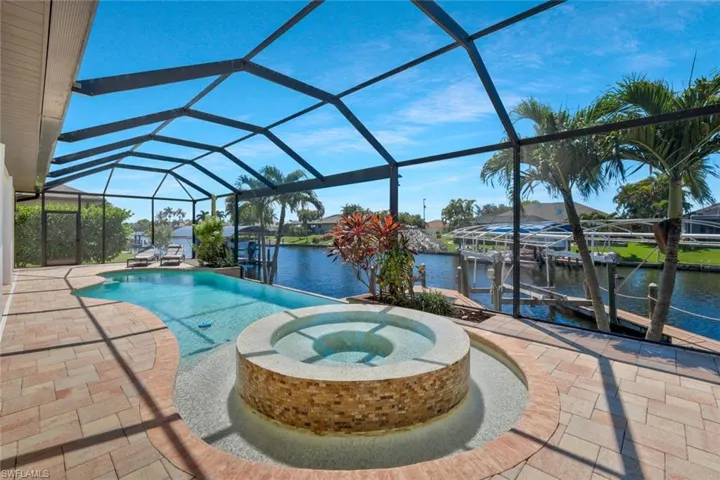 View of swimming pool featuring a sunroom, a water view, a patio area, and a dock