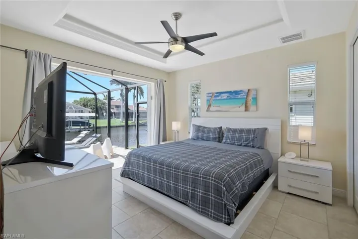 Bedroom featuring a raised ceiling, light tile patterned floors, and access to outside