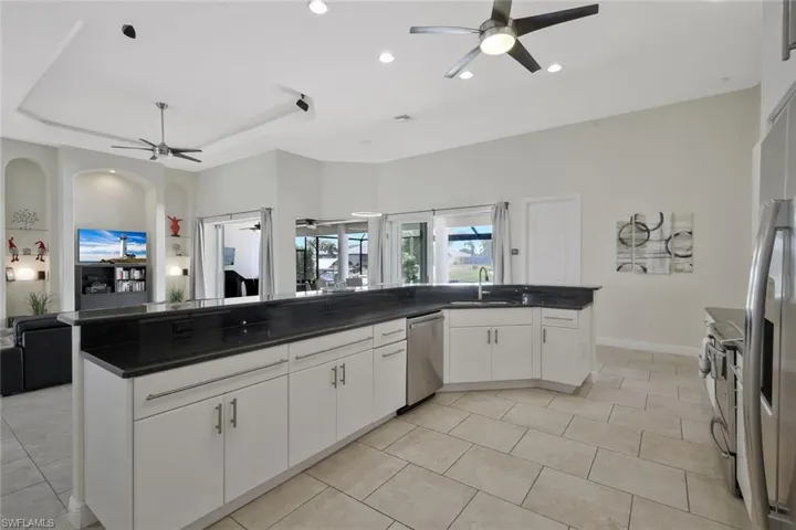 Kitchen with white cabinetry, open floor plan, a ceiling fan, stainless steel appliances, and recessed lighting