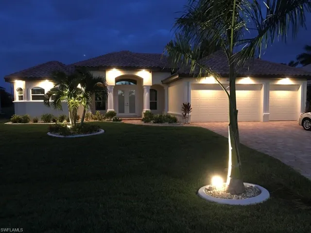 View of front facade featuring french doors, decorative driveway, a yard, stucco siding, and a garage