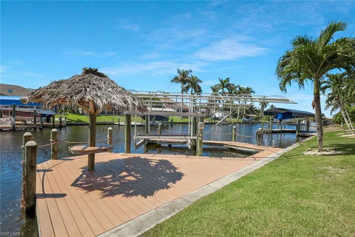 Dock featuring boat lift, a yard, and a water view