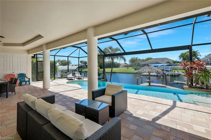 Swimming pool featuring a water view, a patio, a sunroom, and a lanai