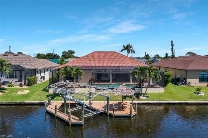 Dock with boat lift, a lanai, a patio area, and a yard
