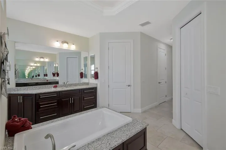 Full bathroom featuring vanity, a bath, light tile patterned floors, a closet, and crown molding
