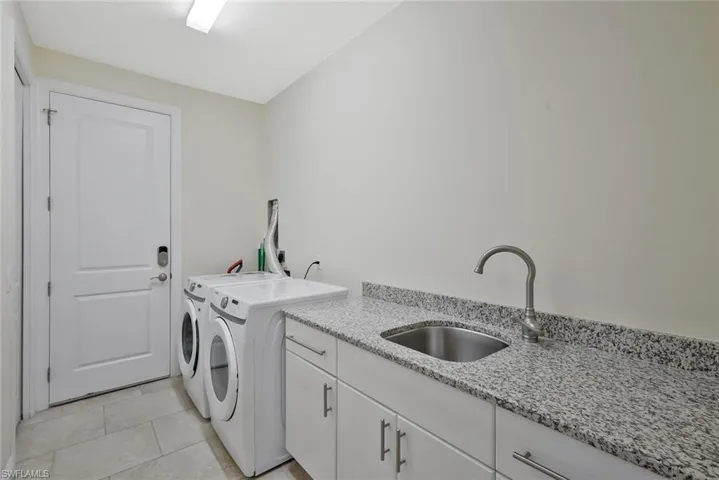 Laundry area with cabinet space, washing machine and clothes dryer, and light tile patterned floors