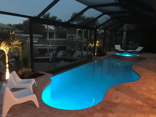 View of swimming pool with a lanai, a sunroom, a pool with connected hot tub, and a patio
