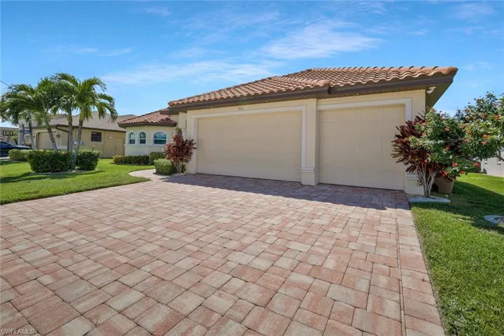 Mediterranean / spanish house with a front lawn, decorative driveway, stucco siding, an attached garage, and a tiled roof