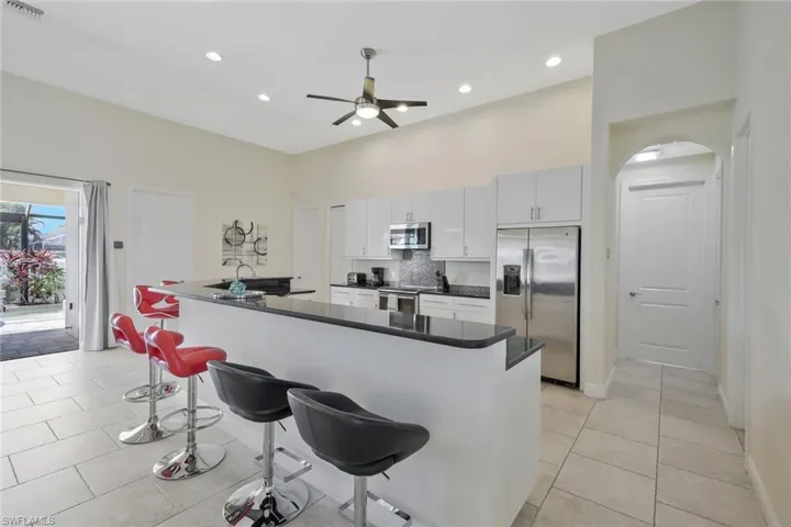 Kitchen with a kitchen breakfast bar, appliances with stainless steel finishes, decorative backsplash, ceiling fan, and light tile patterned floors