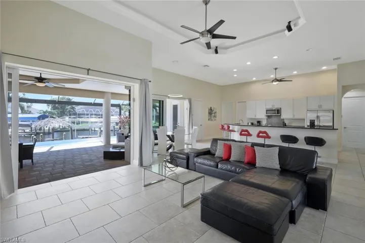 Living room featuring ceiling fan, recessed lighting, a high ceiling, a water view, and a tray ceiling