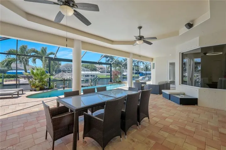 View of patio with a water view, a sunroom, a lanai, a ceiling fan, and an outdoor pool