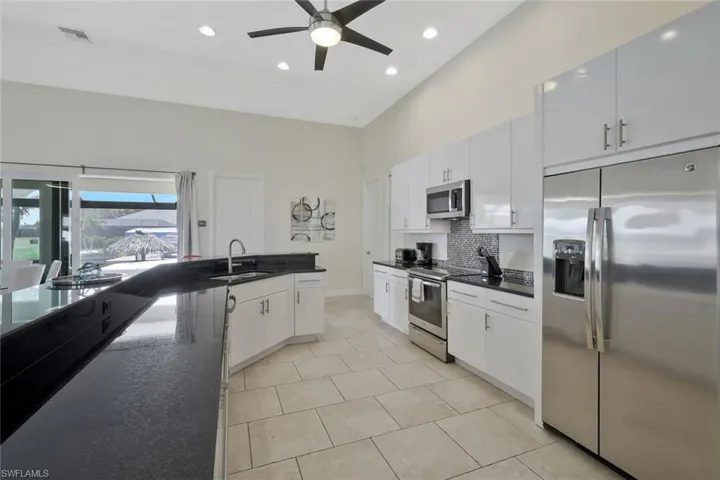 Kitchen with stainless steel appliances, backsplash, recessed lighting, white cabinetry, and ceiling fan